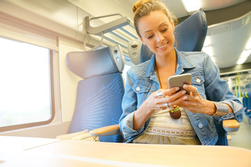 Young woman traveling in train using smartphone