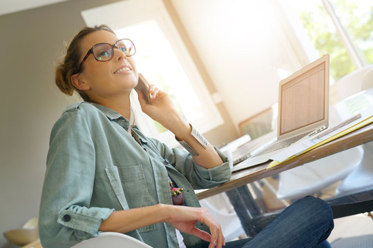 Trendy designer girl talking on phone, home-office