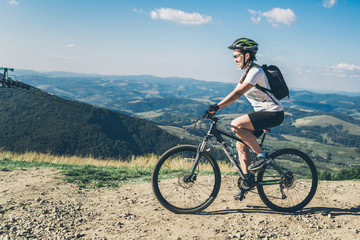 Fototapeta premium Young woman riding on MTB in mountains