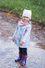 Little girl staying in the puddle