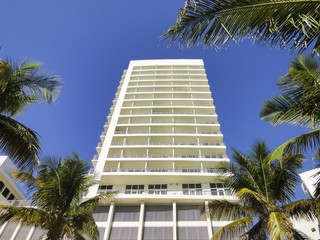Fototapeta na wymiar White modern apartment building with palm trees and blue sky.
