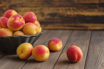 Ripe apricots in basket on wooden background