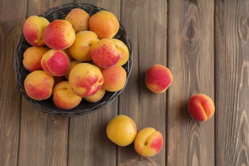 Ripe apricots in basket on wooden background
