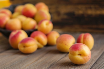 Ripe apricots in basket on wooden background