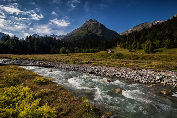 mountain river and wooden hut at the foot of the mountain