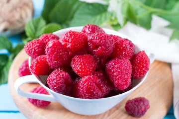 Fresh raspberries in a bowl on a wooden background