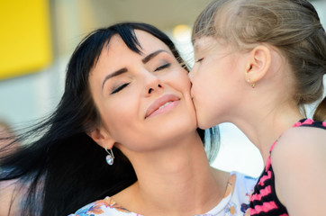 Mother and daughter on the street, portrait of a kiss