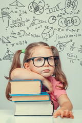 beautiful cute little genius girl with books. Math formulas, problems over her head
