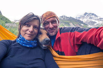 Funny travelers with big smiling dog, taking selfie on the mountains