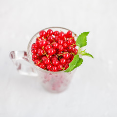 Red currant with mint on a white background. Top view. The concept is healthy food, vitamins, diet and vegetarianism.