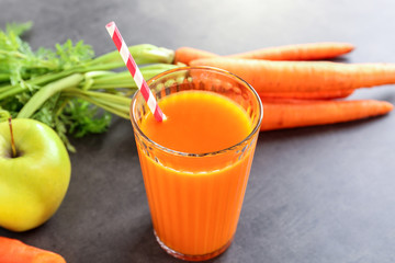 Glass of tasty juice with fresh carrot and apple on grey background