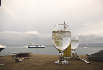 A glass of water and orange juice by the beach