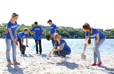 Group of young people cleaning beach area. Volunteer concept