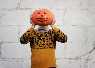 Funny orange pumpkin head close-up that the girl holds in her hands instead of her head