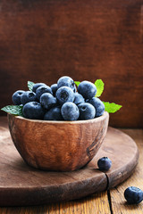 Blueberry in wooden bowl on rustic background.