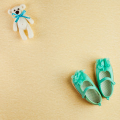 Fototapeta na wymiar Square background with bear toy and turquoise shoes for baby girl
