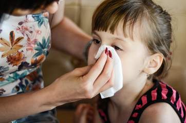 Sleepy girl crying, mother wipes tears with a handkerchief