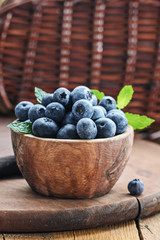 Blueberry in wooden bowl on rustic background.