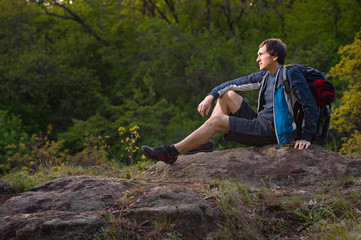 Hiker man takes a rest during summers expedition. Travel, vacation, holidays and adventure concept.