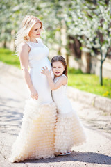 Pregnant mother and her small daughter have fun outdoor. Family look portrait