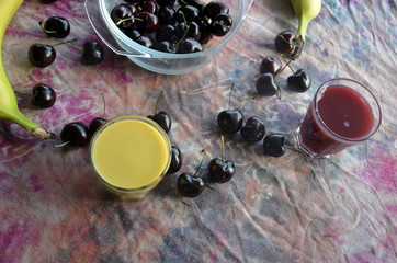 Cerises, bananes et smoothies sur fond chamarré rose et violet