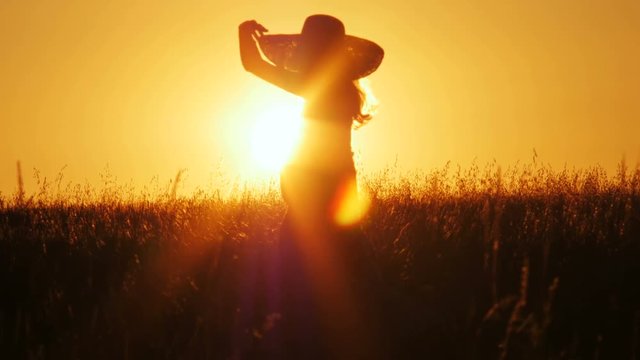 Attractive young woman silhouette dancing outdoors on a sunrise with sun shining bright behind her on a horizon. 4k shot