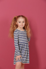 Obraz na płótnie Canvas Small girl in striped dress on pink background