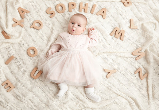 Cute baby with word SOPHIA lying on soft blanket. Choosing name concept