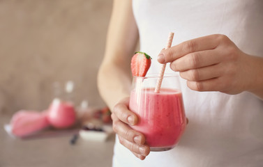 Young woman holding glass of fresh strawberry yogurt smoothie, closeup