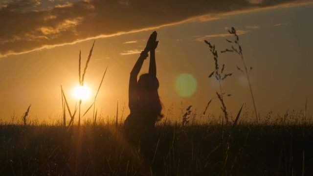 Young woman silhouette doing yoga during sunrise. 4k shot