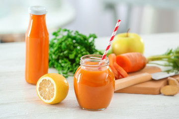 Jar and bottle of fresh carrot juice on table in the kitchen