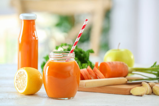 Jar and bottle of fresh carrot juice on table in the kitchen