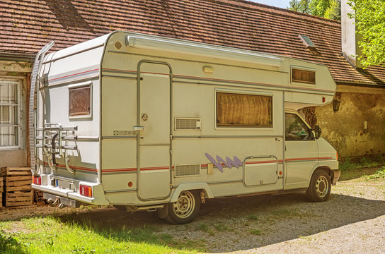 Old vintage camper van. Retro holiday caravan camper, parked in a backyard of a house.

