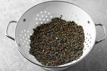 Collander with raw lentils on table, closeup