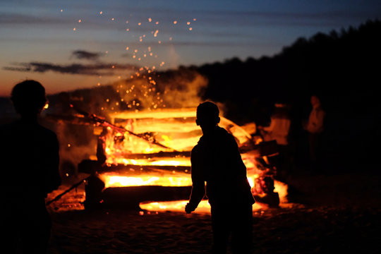 Silhouettes of children against the background of a large fire at the celebration of the summer solstice. Latvia.