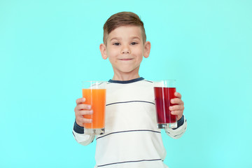 Cute little boy with glasses of juice on color background