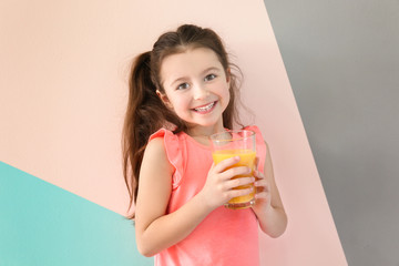 Cute little girl with glass of juice on color background