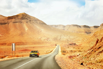 The yellow taxi rides along the mountain road in the Mid Atlas Mountains. Africa. Morocco.