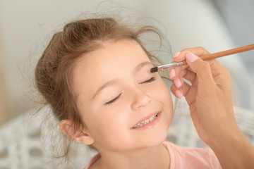 Young woman making up her daughter at home