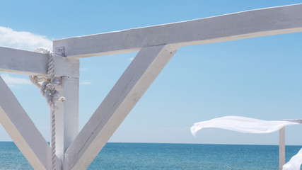 wind blows white curtains on a canopy on the beach