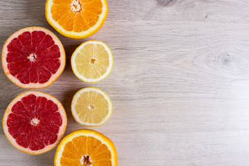 Citrus fruits cut background- oranges, lemons, grapefruit on a bright wooden background