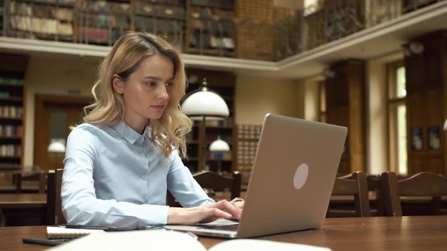 Student works with books and laptop in the library