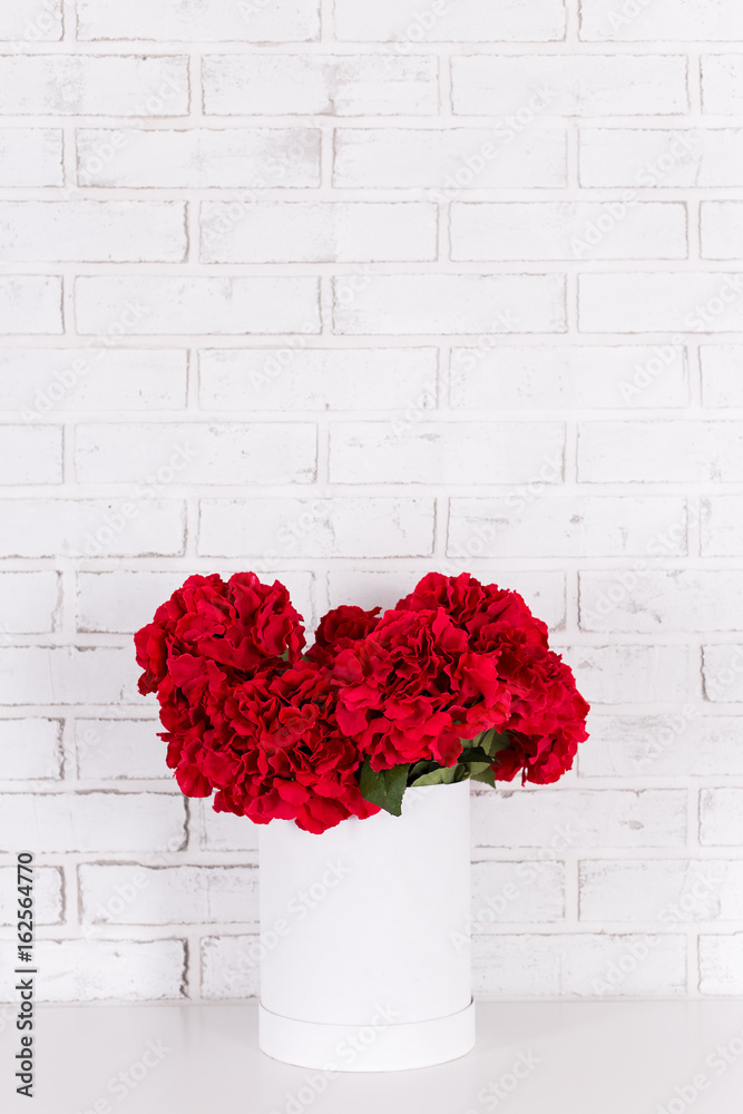 Wall mural bouquet of beautiful red flowers in vase over brick wall