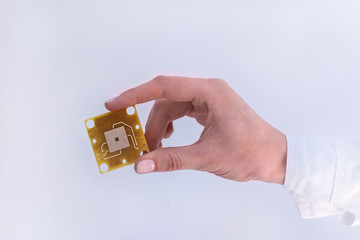 a small silicon circuit pack Board with metal tracks in hand on white background