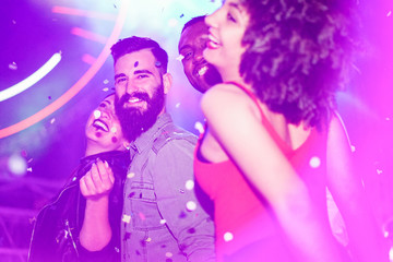 Happy friends having fun in night club with canon ball throwing confetti - Young people enjoying weekend nightlife with original laser lights color - Soft focus on bearded white man - Warm filter