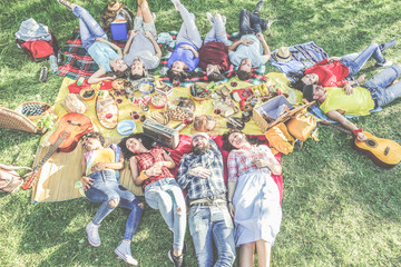 Happy friends lying down at picnic with barbecue on city park outdoor - Young people eating enjoying time together in summer time - Focus on bottom guys  - Youth concept - Contrast filter