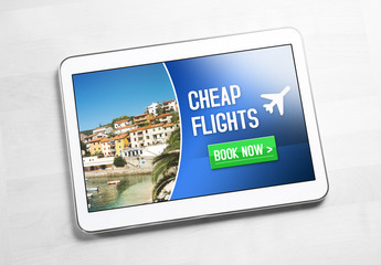 Cheap flights for sale on internet. Top view to tablet on wooden table with affordable and inexpensive vacation offer on screen. Imaginary low cost carrier application on mobile device. Book now.