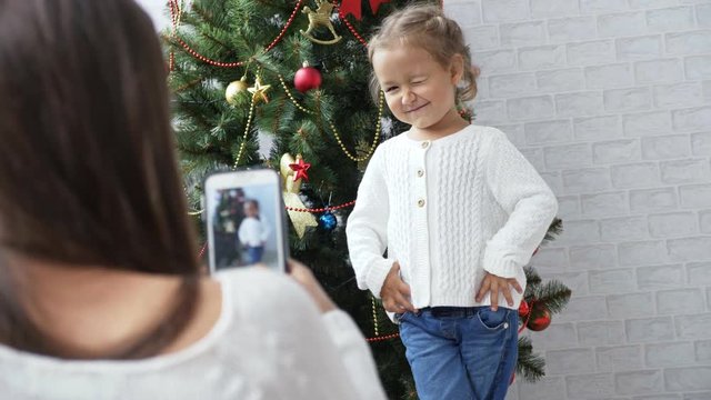 Cheerful little girl dancing and playing the ape near Christmas tree