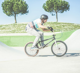 Bmx biker getting ready for jumping in city skate park outdoor - Young trendy man performing skills and tricks with special bicycle - Extreme sport concept - Focus on him-  Warm contrast filter