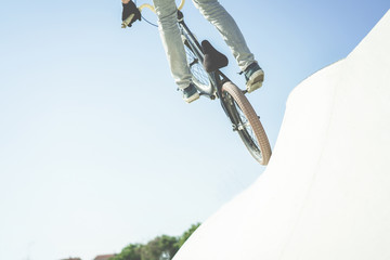 Bmx biker jumping in city skate park outdoor - Young trendy man performing skills and tricks with special bicycle - Extreme sport concept - Focus on bottom wheel - Warm contrast filter